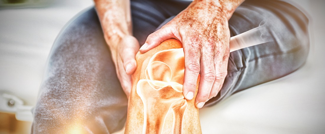 Close-up of hands applying red light therapy on a knee joint to alleviate pain.